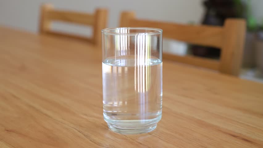 Adding vitamin C powder to a glass of water. Concept of taking vitamins and natural supplements.