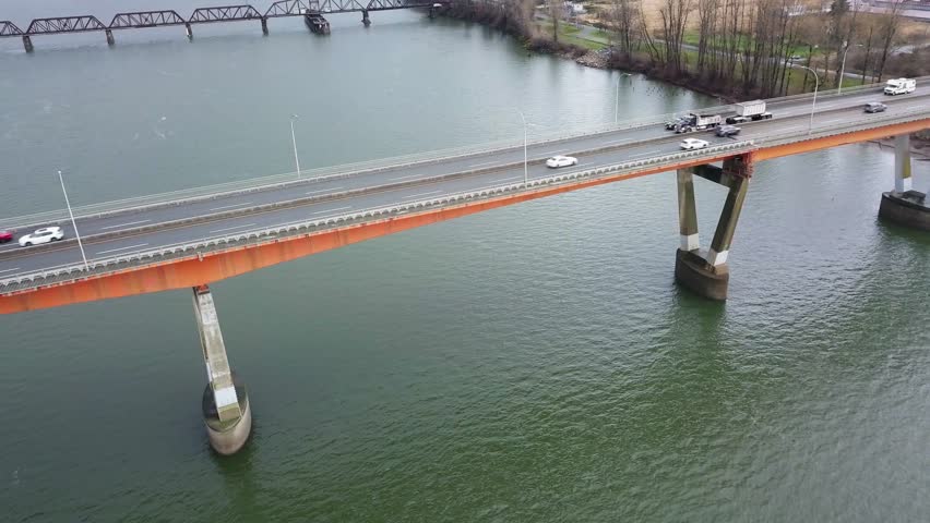 Mission Bridge, Pan From Matsqui to Mission, over the Fraser River in British Columbia. Cars Driving Across Bridge. Fraser Valley, Lower Mainland. Dump Truck Hauling Load.