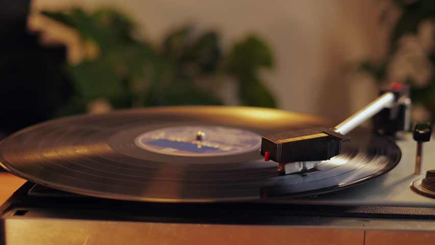 Retro Vinyl record player playing music, close-up macro shot of vintage LP disc old phonograph spinning. Retro music player at home.