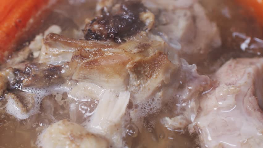 Cooking pot with bone broth meat pork and beef, aspic north food. Vegetables cooking ingredients and spices on kitchen table. 