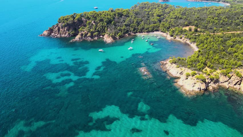 Aerial view of Îles d'Hyères - France, Porquerolles Island. Luxury yachts, spectacular landscape with small water bays. Turquoises water colour. Famous travel destination. Drone forward.