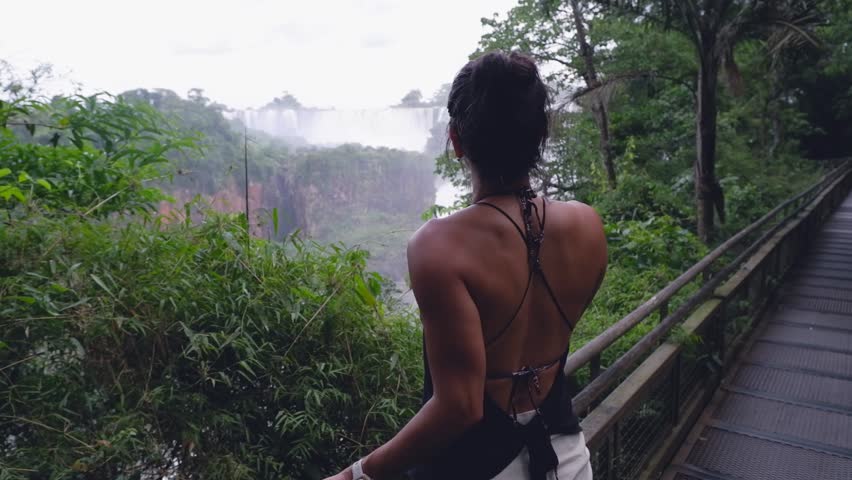 Latin female views majestic Iguazu Waterfall from tourism footpath
