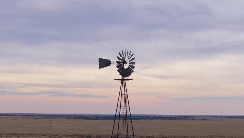 Rustic windmill spinning in Texas landscape with dramatic open sky backdrop