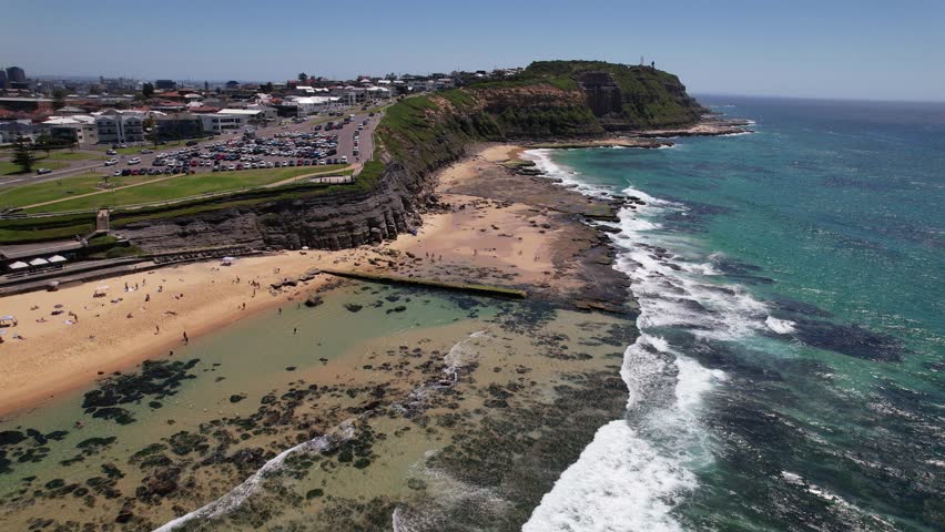 People At Sandy Bar Beach With Waves Splashing In Summer. New South Wales, Australia. aerial pullback shot