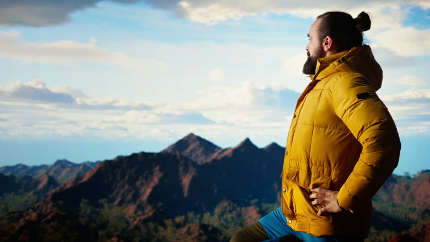 Hiker pauses to admire the panoramic mountain scenery on the hill top, endless sky and rugged peaks creating a breathtaking backdrop for mental clarity. Adventure seeker. Camera A.