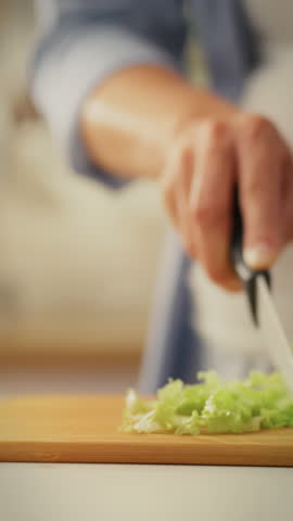 A parent is diligently chopping fresh lettuce in a home kitchen, emphasizing a commitment to healthy eating. This activity highlights the importance of nutritious meals in daily life