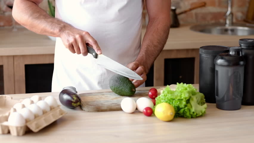 Man Cutting An Avocado And Preparing A Healthy Diet Meal In The Kitchen