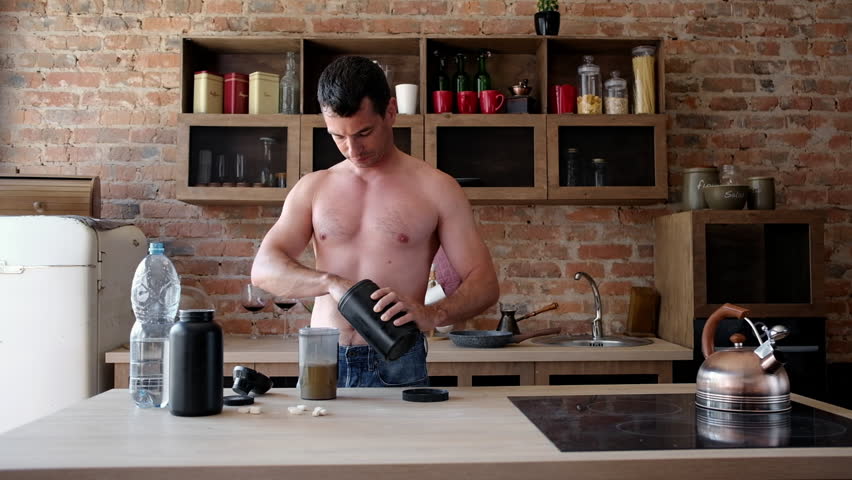 Young Athlete Preparing A Protein Shake In The Kitchen By Adding Scoops Of Protein Powder To The Shaker