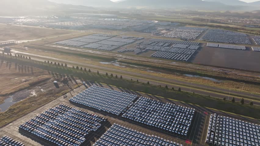 High aerial view of vast parking lot with countless new cars