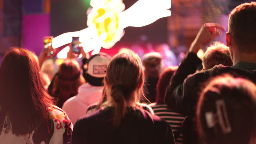 Lot teens dance kpop music concert. Many young men fans cheering fun party. Joy crowd teenagers hang out cool night life fest, k pop chill. Epic live arena. Neon disco light. People enjoy band song.