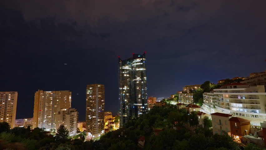 Illuminated skyscraper in residential city at night, Monte Carlo, Monaco. Timelapse