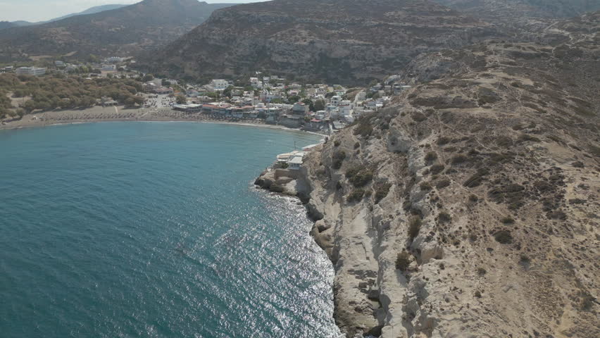 Rocky Cliffs And Seaside Restaurants Matala Beach Crete Greece Drone Descend 4K 60FPS