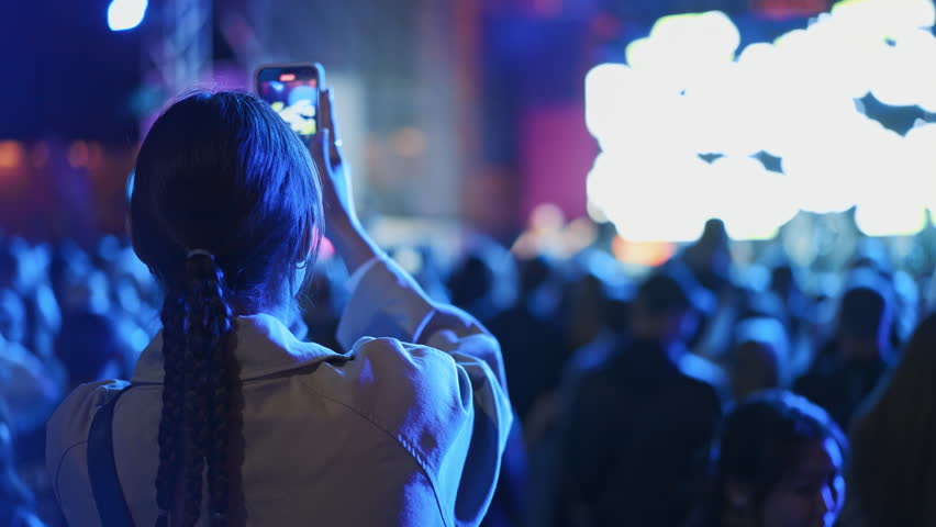 Lot fun people record music video use mobile phone. Fan crowd shoot k pop live concert. Many men hang out cool rave fest. Joy group chill night club hall. Dj star raise hand up. Take neon light photo.