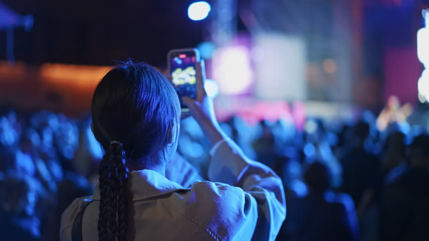 Lot fun people record music video use mobile phone. Fan crowd shoot k pop live concert. Many men hang out cool rave fest. Joy group chill night club hall. Dj star raise hand up. Take neon light photo.