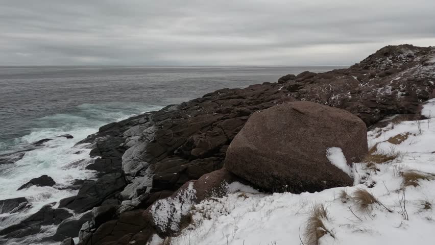 Winter, after snow, cloudy. Easternmost Point of North America, Cape Spear. The cold wind is howling. Brown rocky beach, surging sea. -St. John