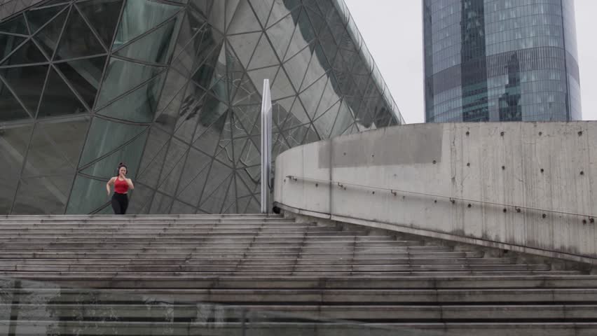 Running woman climbing stairs, sporty activity with modern architectural background