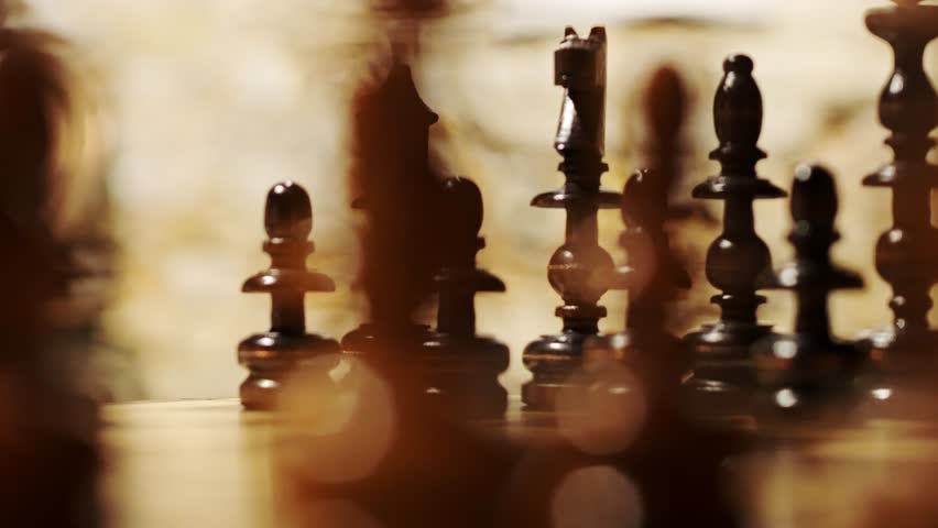 A low-angle shot of wooden chess pieces on a board, bathed in warm lighting 4K