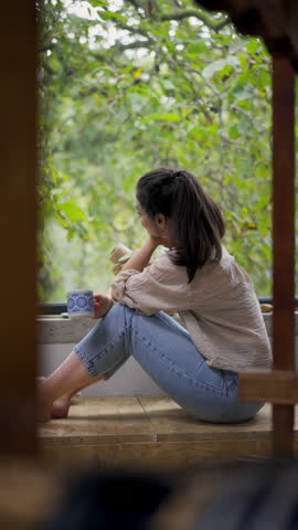 Hygge moment for beautiful woman sitting by a large window. Woman is enjoying time for herself.