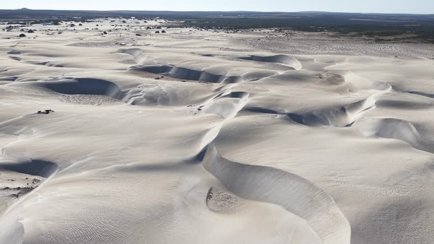 Aerial view of the rolling white gypsum dunes of White Sands National Park, New Mexico, USA. Wind-sculpted formations create a mesmerizing natural pattern under the bright sunlight.