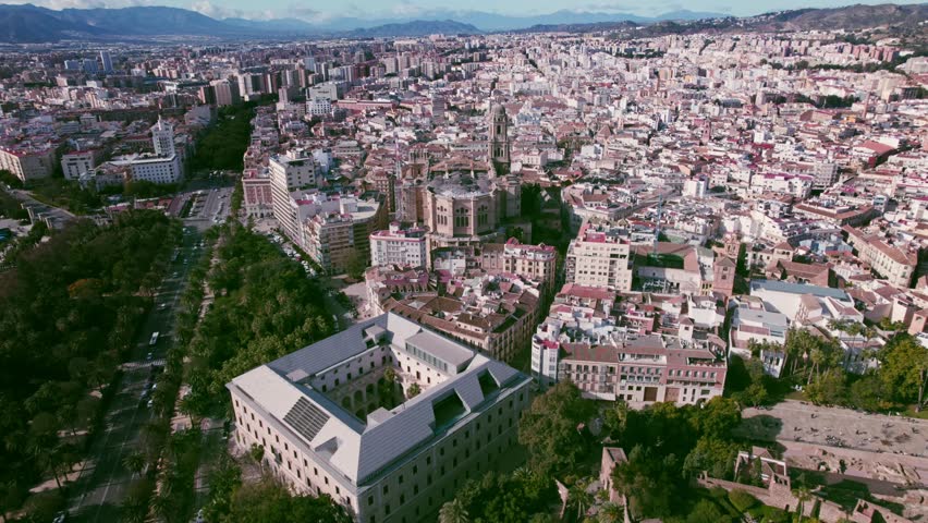 Modern Malaga museum and La Manquita cathedral in historic city center along wide boulevard road with mountain range in the background of Costa del Sol tourist destination