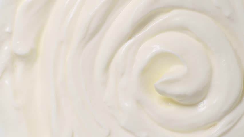 Sour cream or greek yogurt swirl, rotating texture, White cream background, close up. Dairy product. Delicious organic creamy yogurt. Milk cream. Top view, Macro shot. 