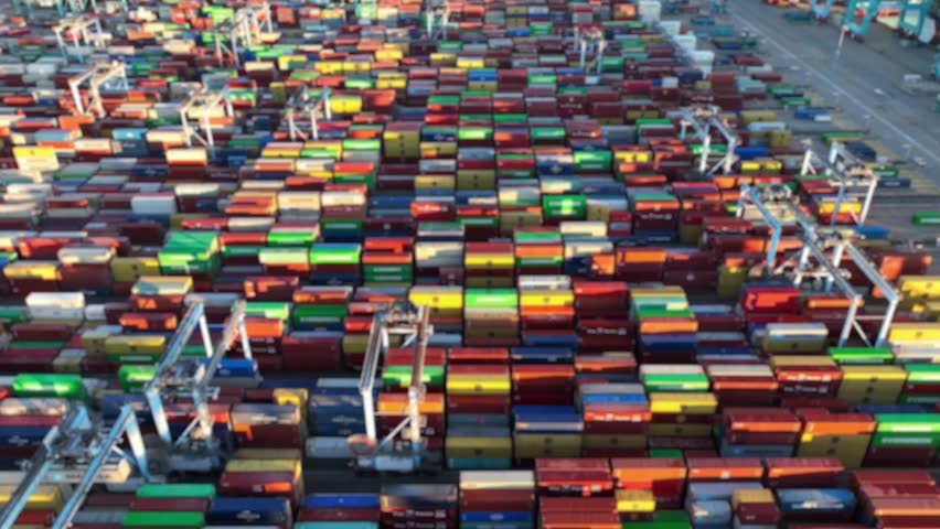 Shipping port with colorful containers. Logistics and distribution theme. Animation of relevant words overlayed blurred aerial footage.