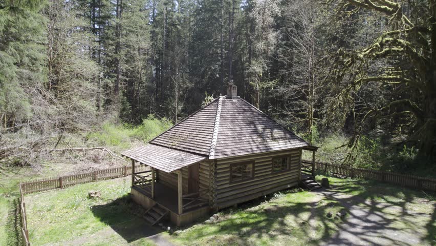 Orbit drone shot of log cabin in the forest at Log Cabin Resort during the day in Olympic National Park, Washington, USA
