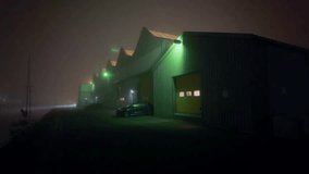 A long row of industrial warehouses at night, lined with green-lit security lamps, creating an atmospheric, misty scene. Location: Amsterdam Noord, Nederland - Powered by Shutterstock - Get 15% off with code: PIKWIZARD15
