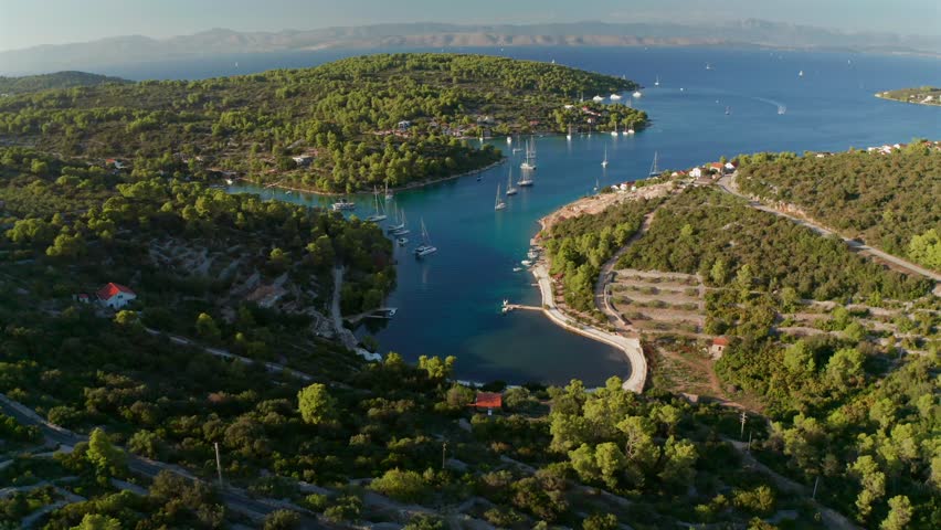 Aerial flyover Mala Maslinica secluded bay with sailboats and lush greenery in Croatia