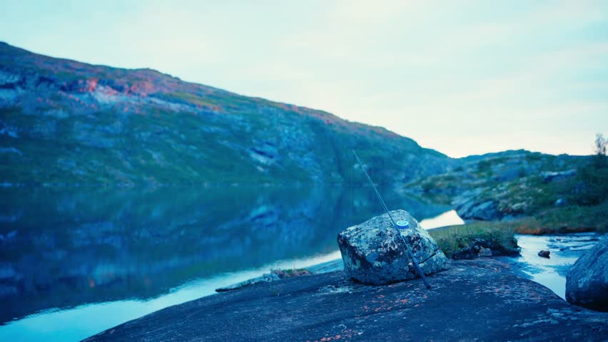 Caucasian Man With A Fishing Rod Over Rocks Near Tranquil Lake In Rago National Park, Norway. Static Shot
