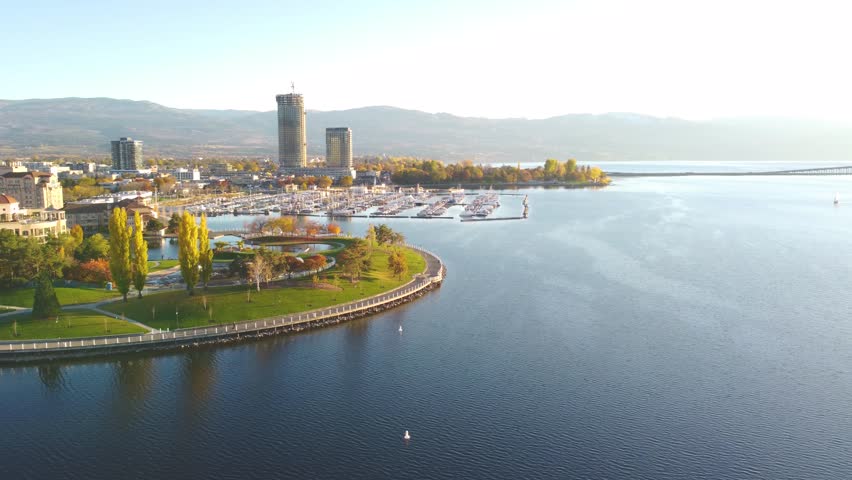 Downtown Waterfront, Kelowna, BC, Canada. Panorama Calm Okanagan Lake Landscape. British Columbia Interior in the Fall Autumn Season with Colourful Trees. Evening Sunset, City Park Walking Path