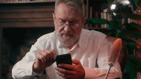 Old Caucasian man user mobile phone smartphone cellphone gadget online messaging social networks male businessman business home senior browsing chatting entrepreneur app office indoor mature pensioner - Powered by Shutterstock - Get 15% off with code: PIKWIZARD15