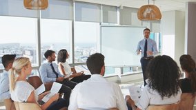 Businessman standing at whiteboard giving presentation to business team sitting around table in modern office - shot in slow motion - Powered by Shutterstock - Get 15% off with code: PIKWIZARD15
