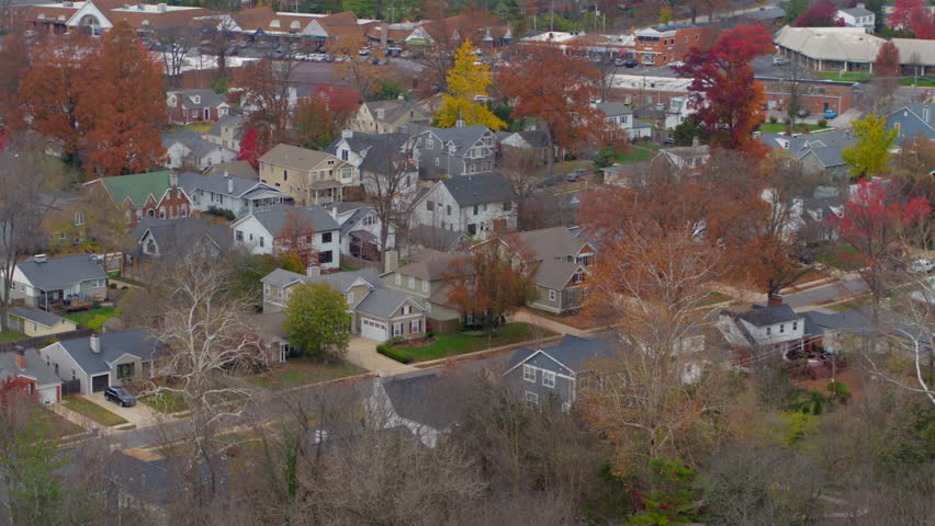 Beautiful aerial approaching houses in a picturesque Ladue subdivision in St. Louis, Missouri, during autumn. Captures vibrant fall foliage, suburban elegance, and serene residential charm.