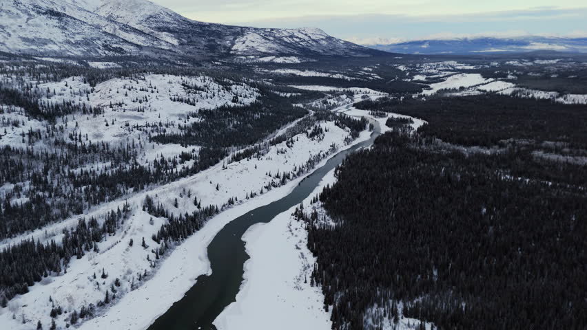 Takhini River Through Snow With Surrounding Mountains In Winter. Yukon, Canada. aerial shot
