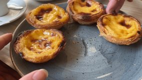 A golden Portuguese custard tart displays its perfectly caramelized top and flaky pastry layers, with the creamy custard filling catching the light. - Powered by Shutterstock - Get 15% off with code: PIKWIZARD15