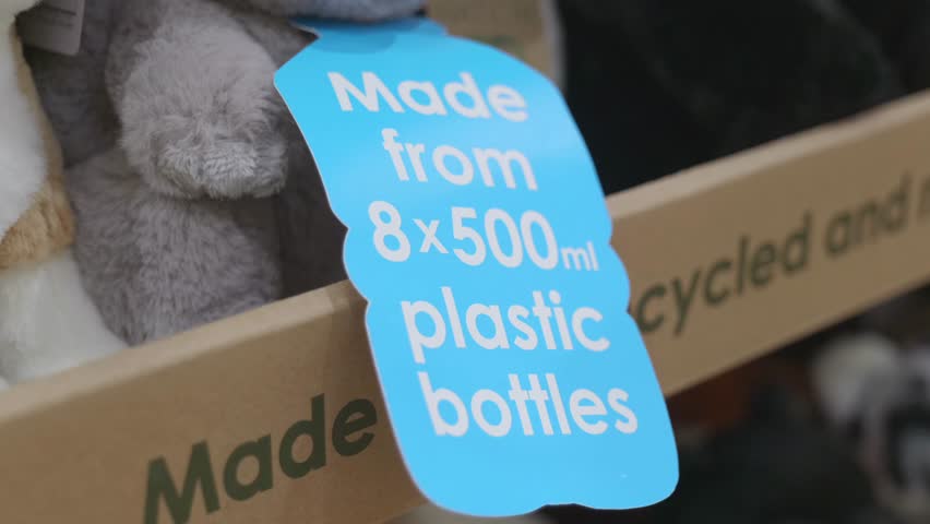 A close-up of a plush toy with a sign indicating it is made from recycled plastic bottles. A sustainable and eco-friendly product showcased at a toy fair.