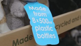 A close-up of a plush toy with a sign indicating it is made from recycled plastic bottles. A sustainable and eco-friendly product showcased at a toy fair. - Powered by Shutterstock - Get 15% off with code: PIKWIZARD15