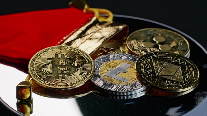 Shiny coins representing bitcoin, ripple, litecoin, and ethereum cryptocurrency turning slowly on silver turntable.