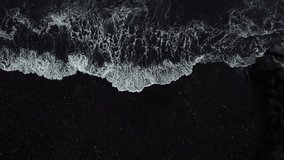Crashing foamy ocean waves create stunning textures and intricate patterns on black sand beach in Ponta do Sol, Madeira island, Portugal, capturing the beauty of nature's artistry, top down drone shot - Powered by Shutterstock - Get 15% off with code: PIKWIZARD15
