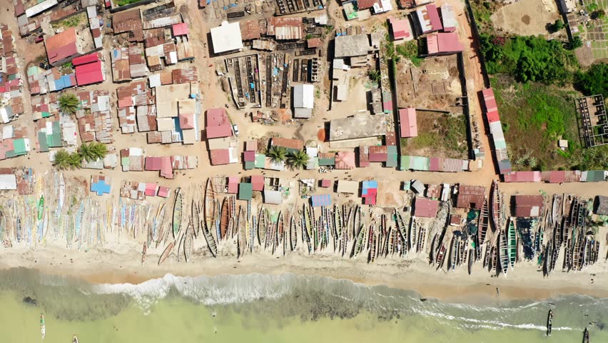 Aerial top down shot of fisherman and boats in Tanji fishing center village in Tanyeh, Gambia West Africa, 4K drone