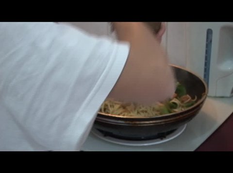 person is cooking noodle with vegetables and meat
