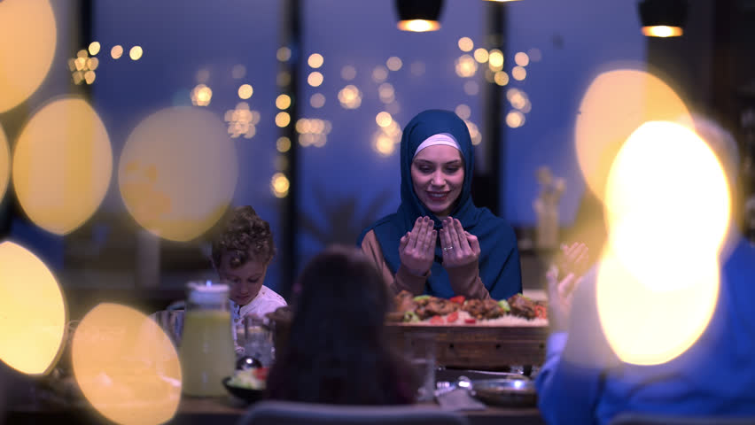 A diverse European Islamic family gathers together for iftar to break fasting during Ramadan, embracing cultural harmony and unity over Middle Eastern cuisine, warm lighting, Eid Mubarak dua time
