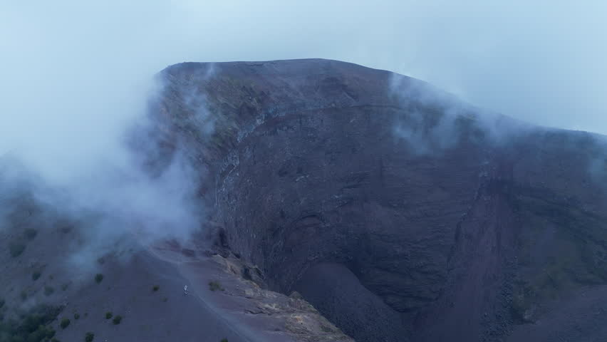 Aerial view of summit and crater of Mount Vesuvius volcano in Italy, mysterious atmosphere on moody and cloudy day
