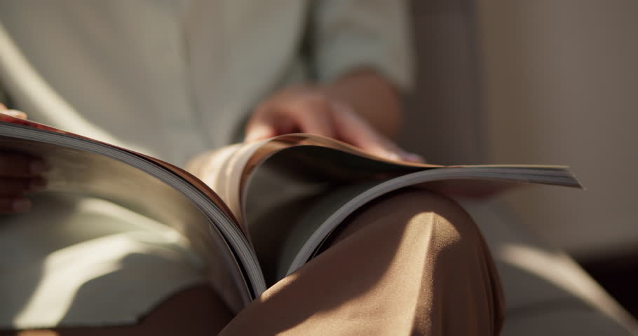 A person enjoys flipping through a magazine in a warm cozy living room.