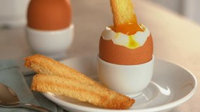 Close up of fresh crispy bread crouton dips in soft-boiled egg in egg cup. Chicken yolk flows down egg. Breakfast concept. Food background - Powered by Shutterstock - Get 15% off with code: PIKWIZARD15
