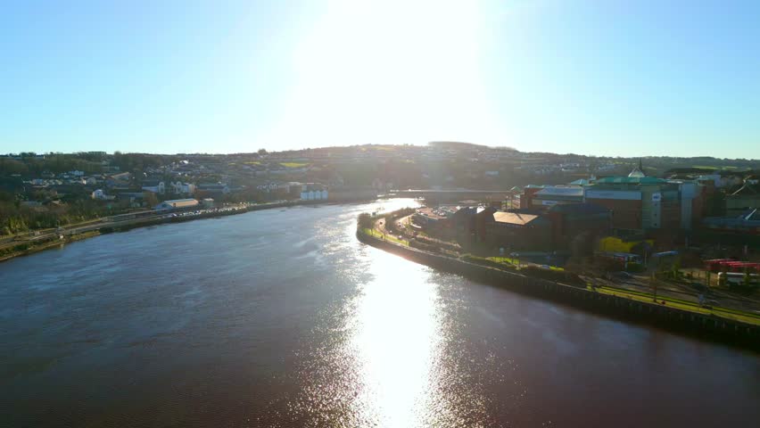 Wide aerial of The Peace Bridge and River Foyle in Derry-Londonderry on a sunny day. The camera reverses to reveal the Peace Bridge. Filmed in 4K, 60fps and with Rec709 color.