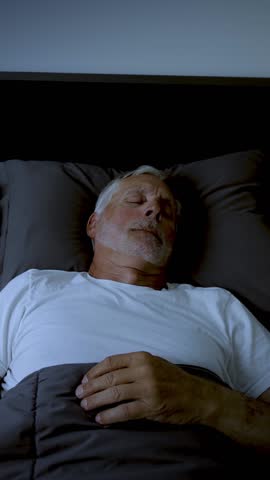 Mature adult sleeping at night. Vertical Video.