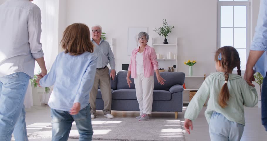Portrait of joyful smiling big family of young parents, senior grandparents and children standing in the living room at home and hugging. Happy family concept. 4k video. Slow motion video.