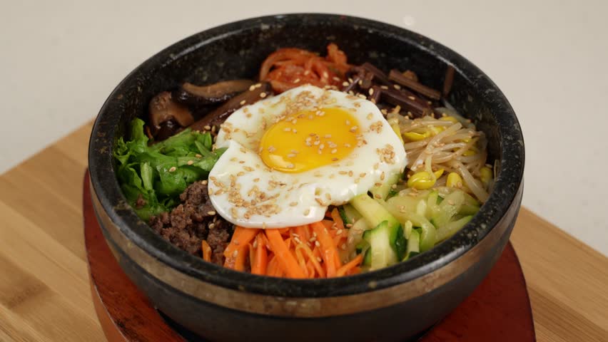 Warm stone bowl with rice, seasoned vegetables, beef, and egg, mixed with spicy sauce. 뜨거운 돌솥에 밥, 나물, 고기, 계란이 어우러진 매콤한 한 그릇.